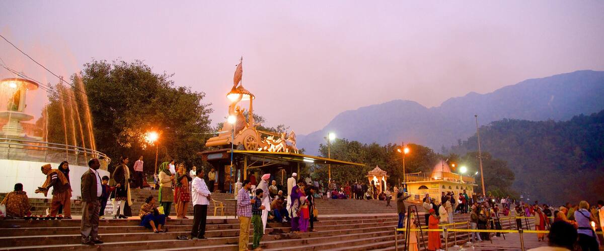A temple with a large statue and steps leading up to it, surrounded by mountains.