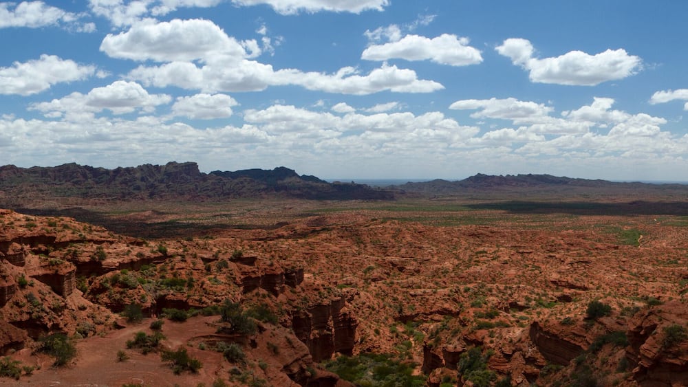 The red canyon. Panorama view of the arid desert, sandstone and rocky cliffs and mountains under a blue sky with clouds.
