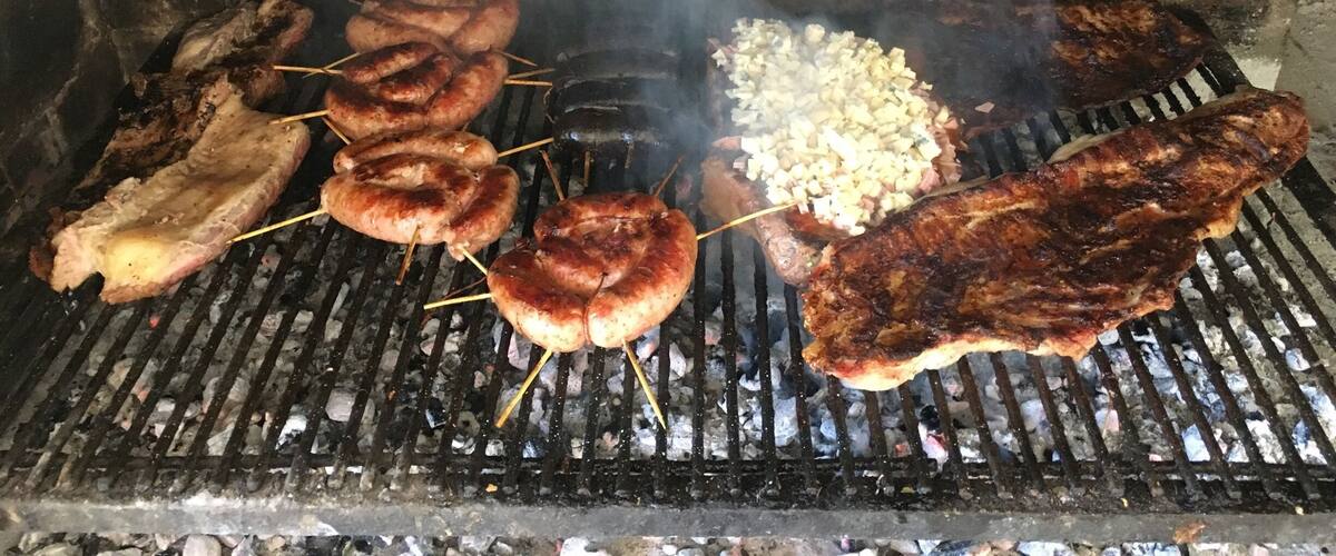 A grill with various meats and vegetables being cooked.