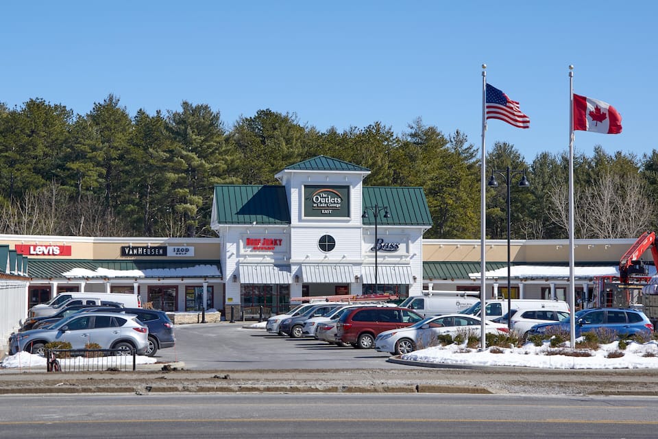 A commercial area with a building labeled "The Outlets" and flags of the USA and Canada.