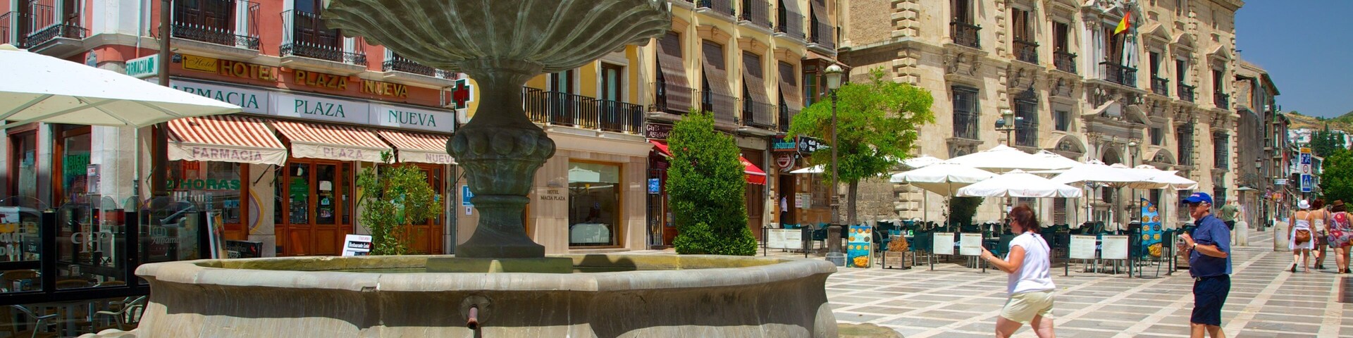A historic plaza with a central fountain, surrounded by colorful buildings and outdoor seating areas.