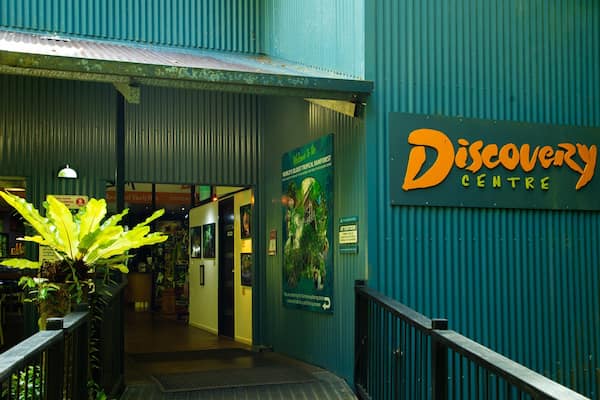 The entrance to the Discovery Centre with a sign, a staircase, and a large potted plant.