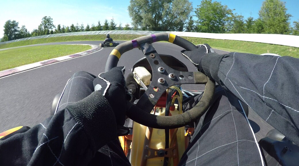 POV: Steering a speeding go cart along the winding asphalt circuit on sunny day.
