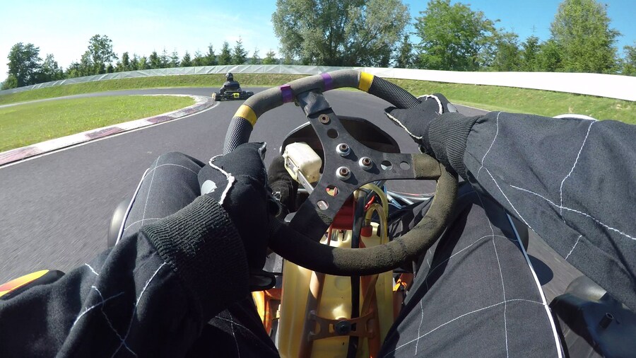 POV: Steering a speeding go cart along the winding asphalt circuit on sunny day.