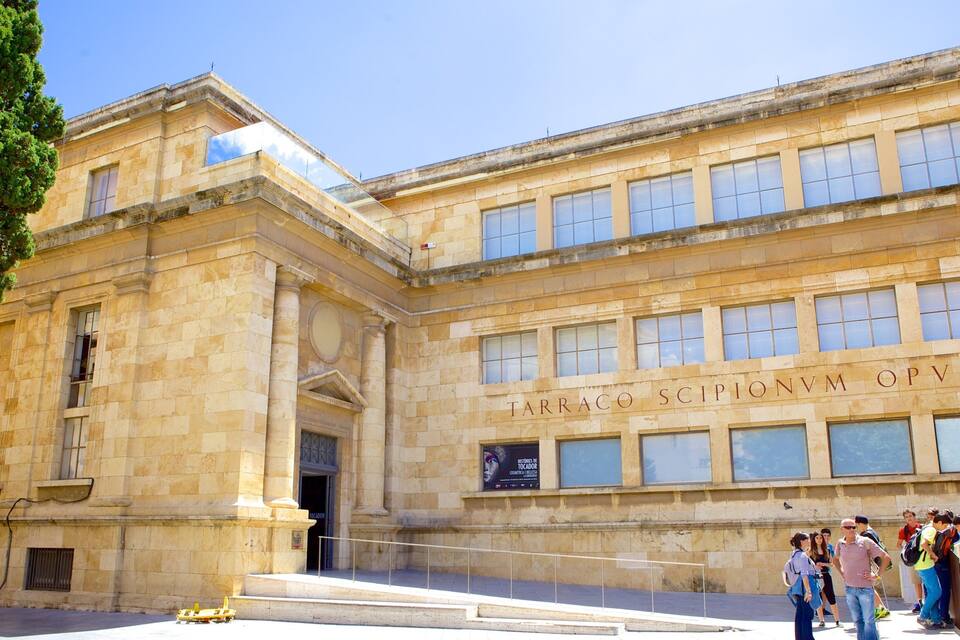 A historic building with classical architecture and a sign reading "TARACO SCIPIONVM OPVS".