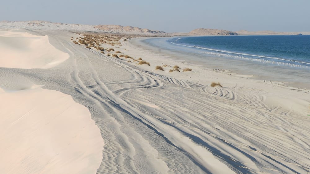 Wüstenlandschaft mit Sanddünen und einem Strand.