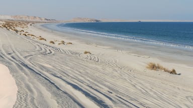 A desert landscape with sand dunes and a beach.