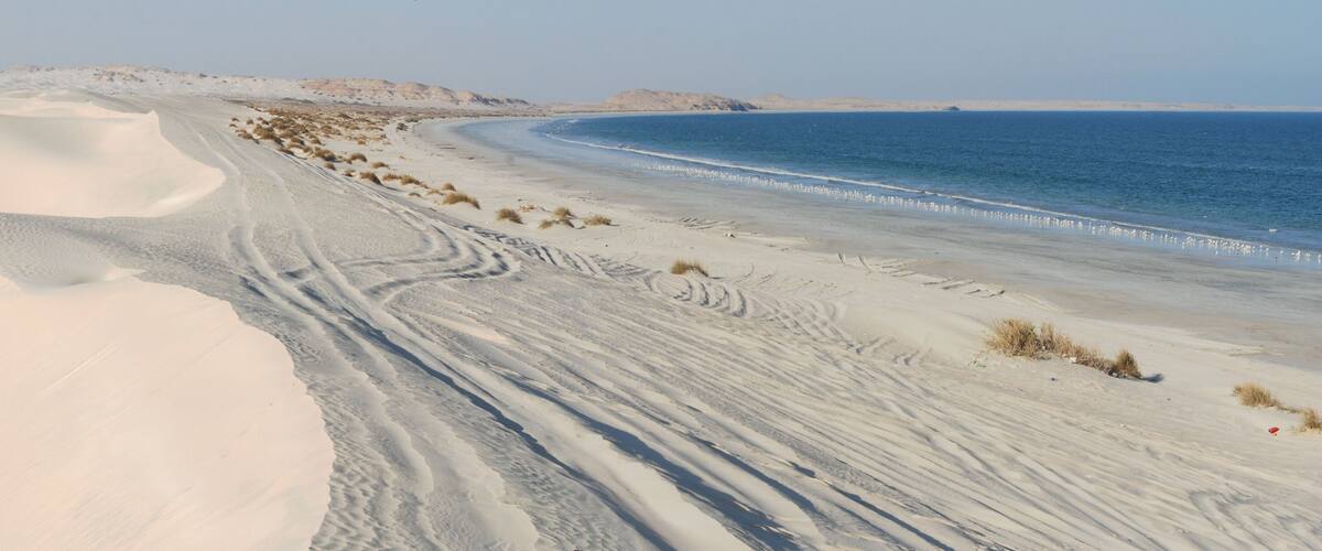 A desert landscape with sand dunes and a beach.