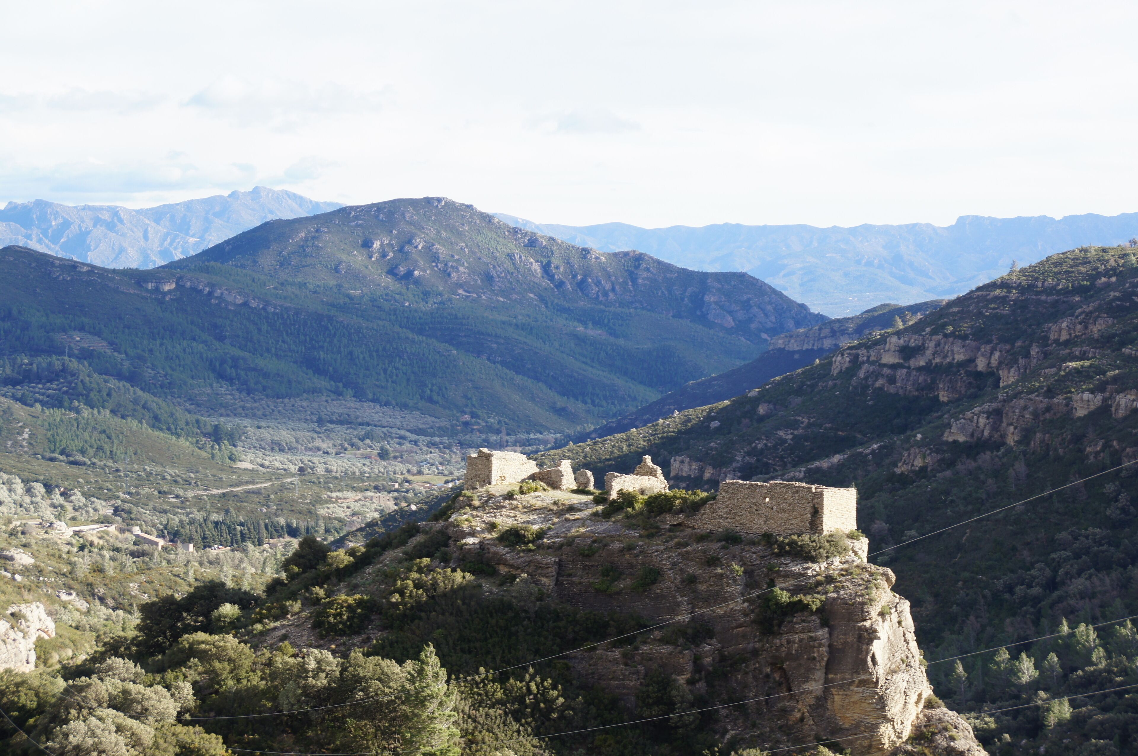 A mountainous landscape with ancient ruins on a cliff.