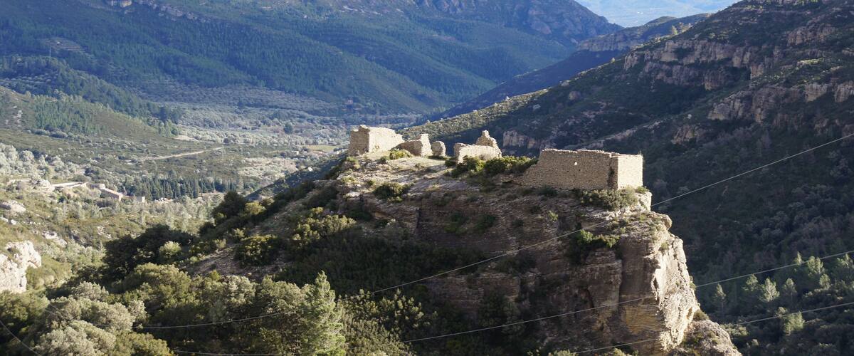 A mountainous landscape with ancient ruins on a cliff.