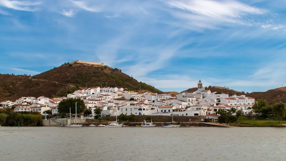 SanlĂșcar de Guadiana a orillas del rĂo Guadiana en la frontera con Portugal. A la izquierda su fortaleza de San Marcos restaurada con su encalado original y a la derecha el campanario de su iglesia.