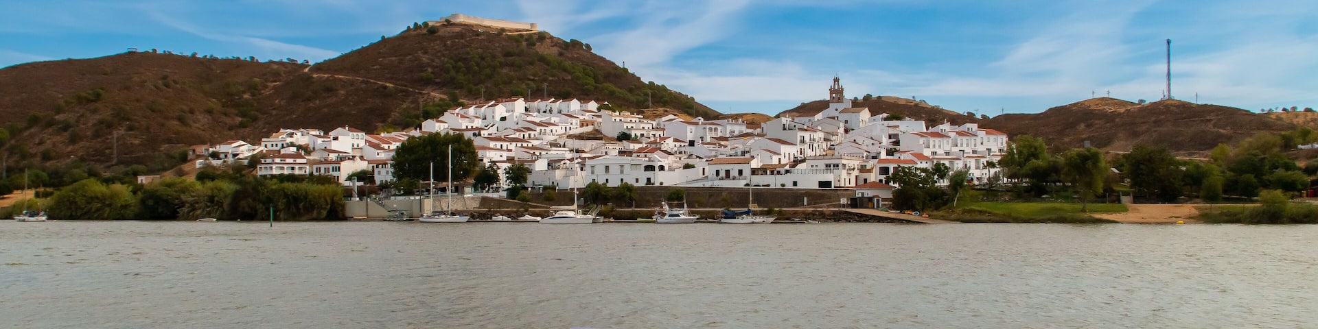 Sanlúcar de Guadiana a orillas del río Guadiana en la frontera con Portugal. A la izquierda su fortaleza de San Marcos restaurada con su encalado original y a la derecha el campanario de su iglesia.