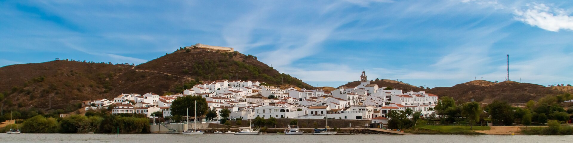 SanlĂșcar de Guadiana a orillas del rĂo Guadiana en la frontera con Portugal. A la izquierda su fortaleza de San Marcos restaurada con su encalado original y a la derecha el campanario de su iglesia.