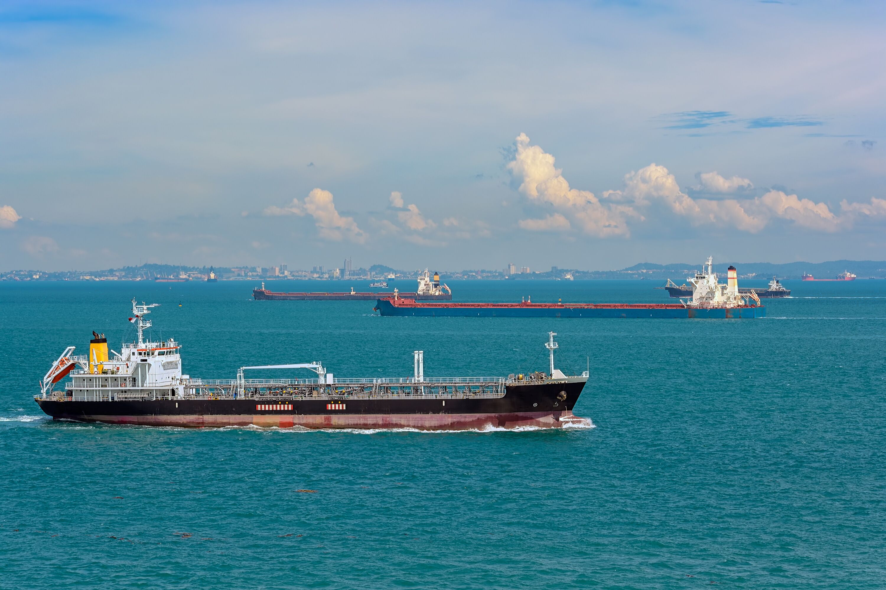 A large cargo ship in the ocean with other ships in the background.
