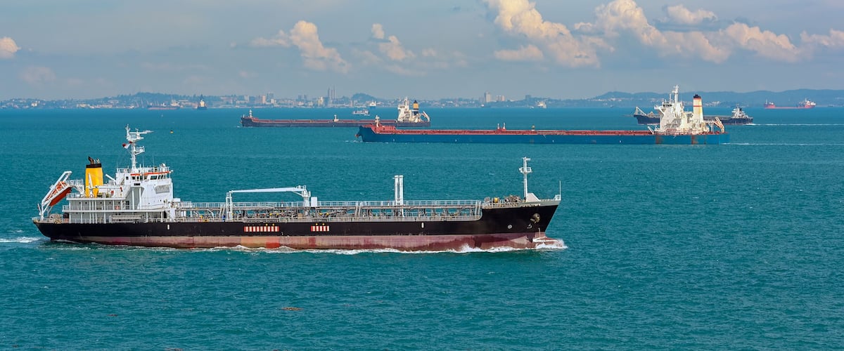 A large cargo ship in the ocean with other ships in the background.