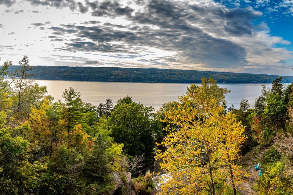 A lake surrounded by autumn foliage, with a cloudy sky above.