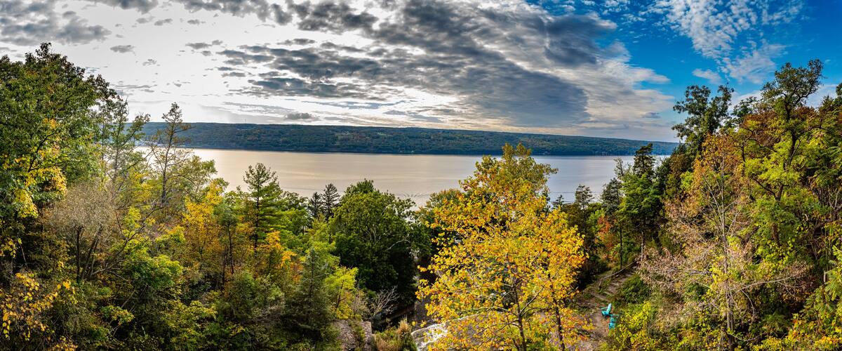 A lake surrounded by autumn foliage, with a cloudy sky above.
