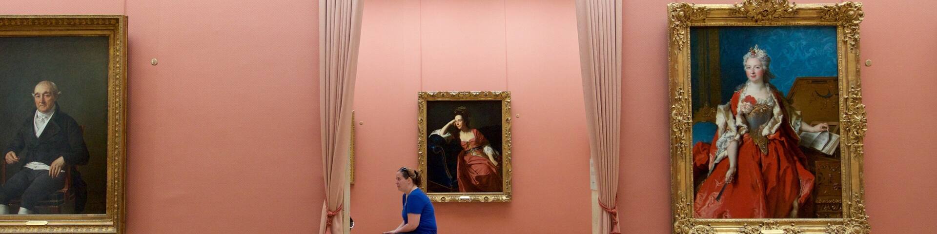 A museum interior with classical paintings, a central bench, and a pink wall.