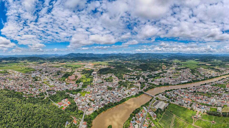 A river winding through a town surrounded by mountains and greenery.
