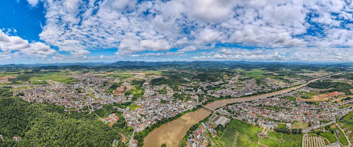 A river winding through a town surrounded by mountains and greenery.