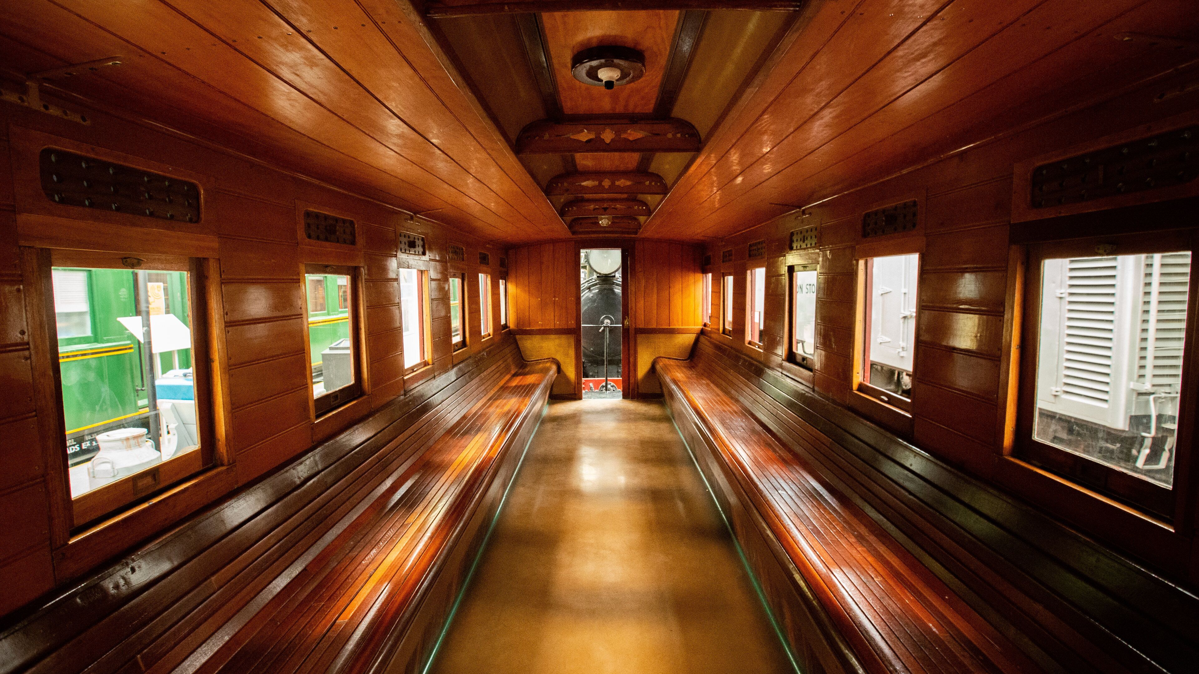 A wooden train carriage with benches and windows.