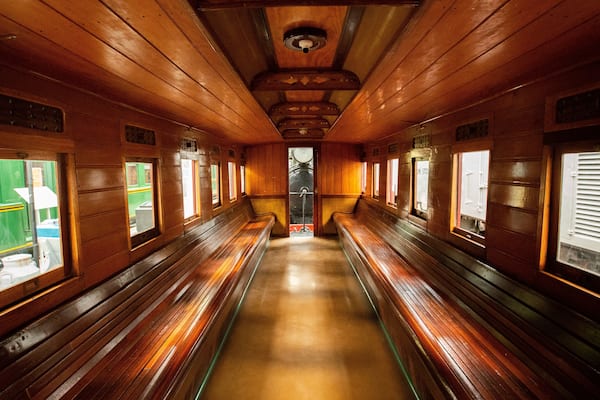 A wooden train carriage with benches and windows.
