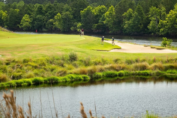 Grand Dunes Golf Course which includes golf and a pond as well as a small group of people