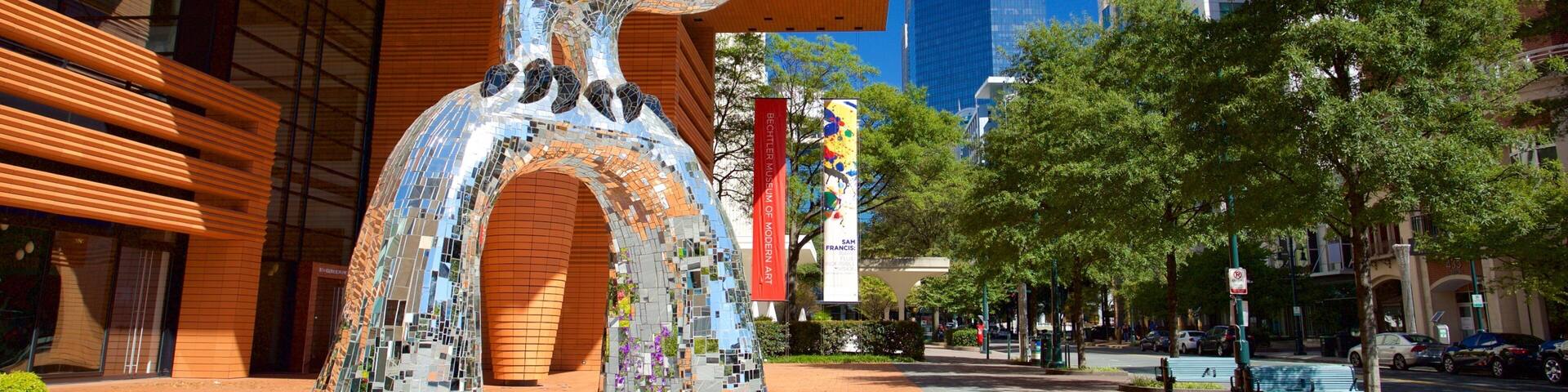 A modern sculpture in a plaza with tall buildings in the background.