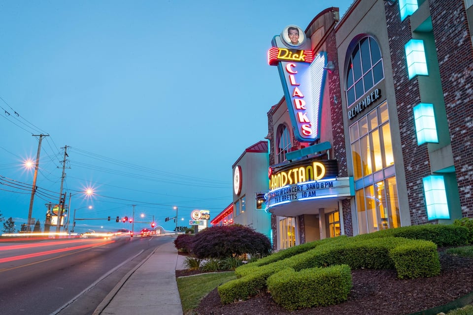 A theater with neon signs, a brick building, and a well-maintained garden.