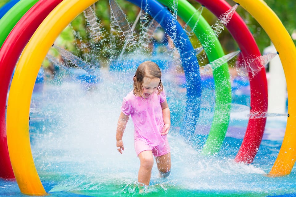 A child playing in a water play area with colorful rings.