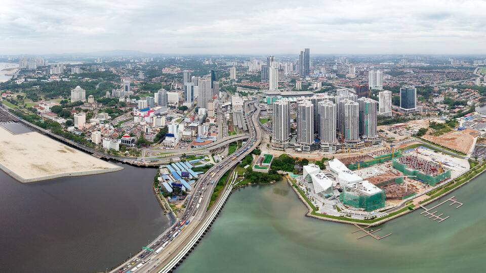 A coastal cityscape with high-rise buildings, a bridge, and a marina.