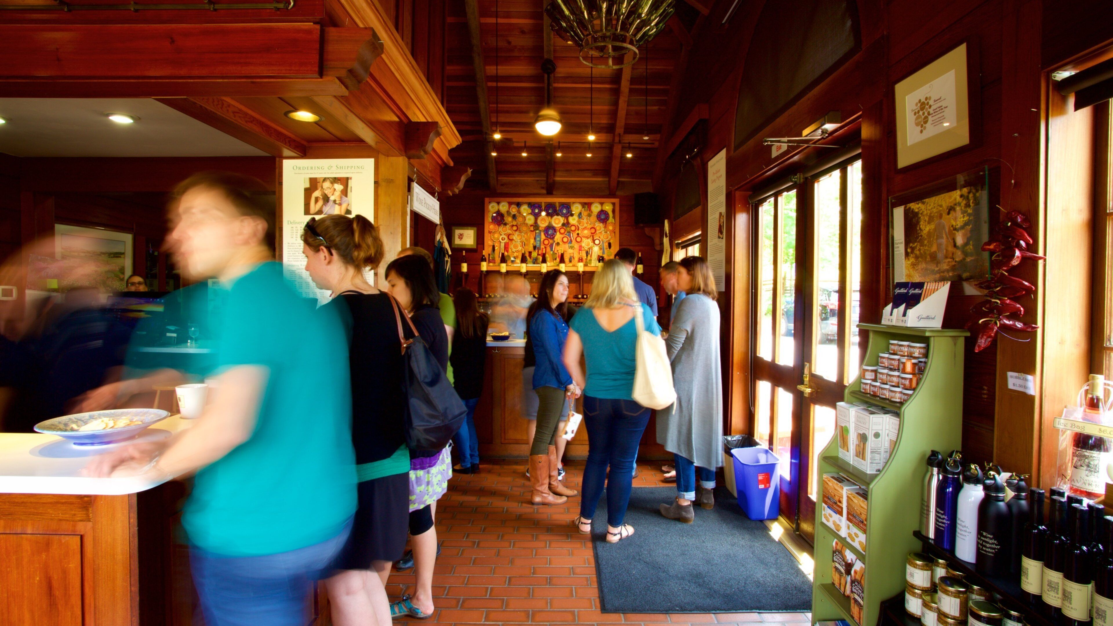 A busy restaurant interior with wooden beams, a bar area, and a display of wine bottles.