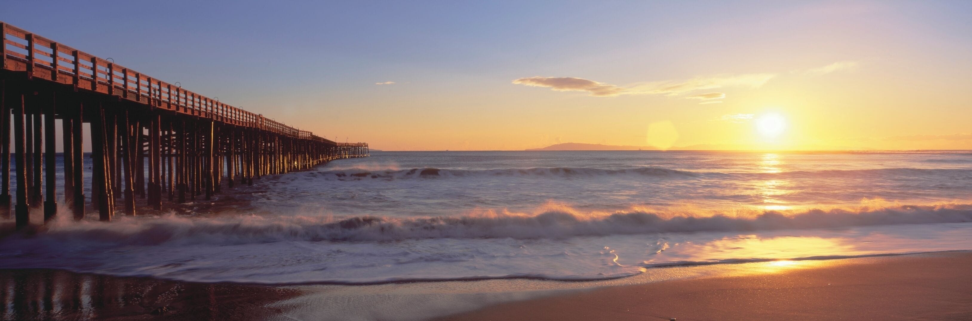 A pier extending into the ocean at sunset.