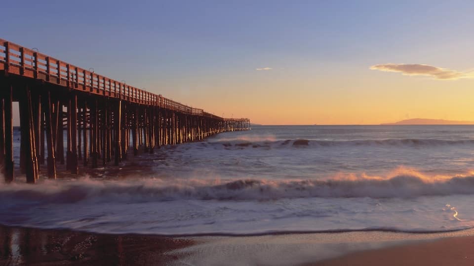 A pier extending into the ocean at sunset.