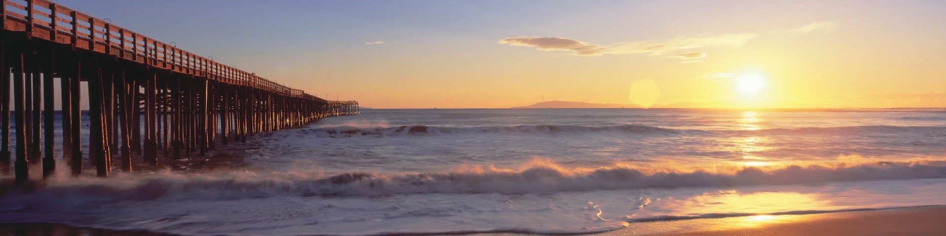 Un muelle que se adentra en el océano al atardecer.