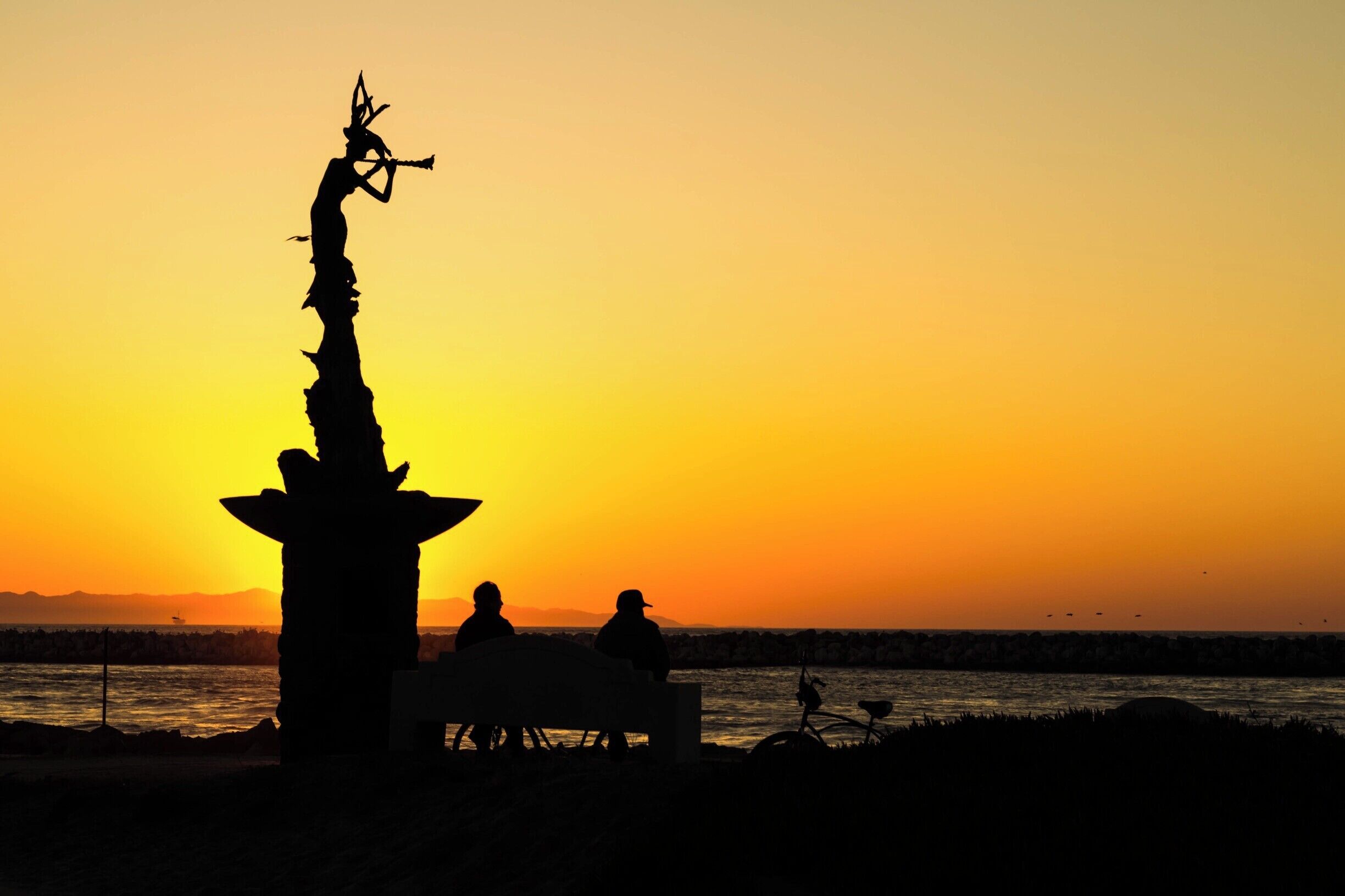 Sunset at Soter Point at the Marina Park in Ventura, California. A bronze statue of a flute-playing mermaid is installed at the end of the walkway. It is a donation to the city from a Russian immigrant. A plaque in the 10 foot pedestal reads, "From Russia With Love".