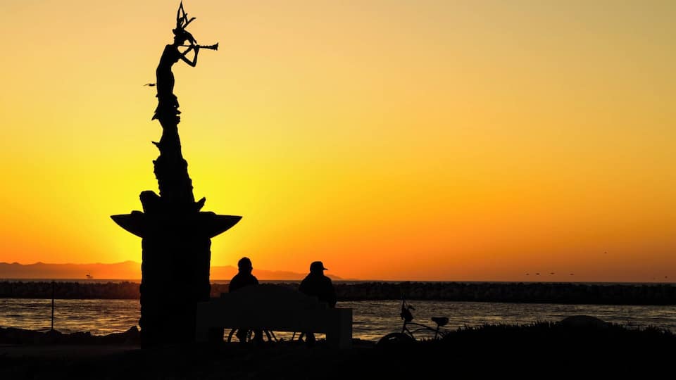 Sunset at Soter Point at the Marina Park in Ventura, California. A bronze statue of a flute-playing mermaid is installed at the end of the walkway. It is a donation to the city from a Russian immigrant. A plaque in the 10 foot pedestal reads, "From Russia With Love".