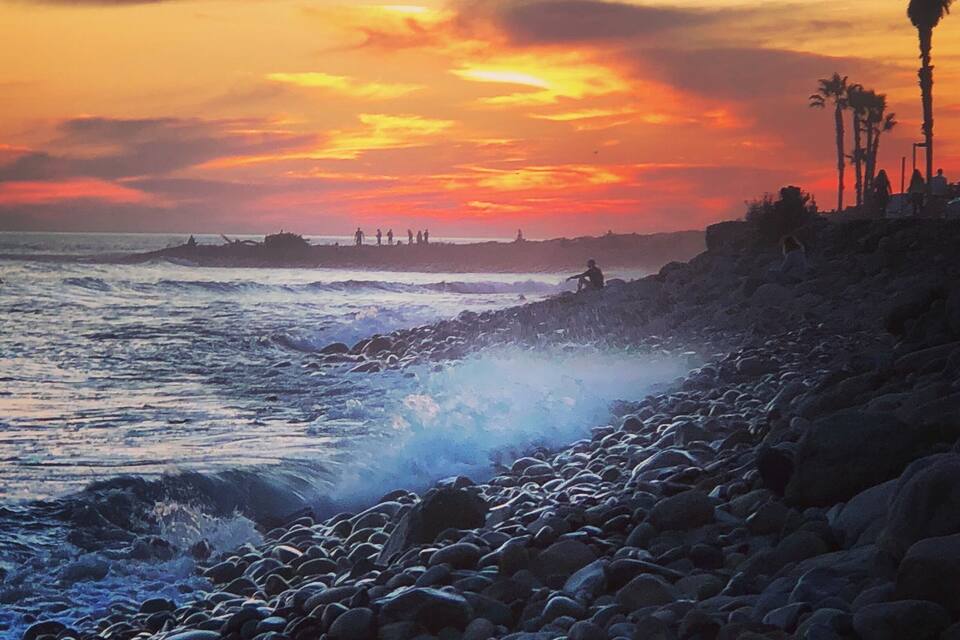 Una playa rocosa con olas rompiendo en la orilla durante el atardecer.
