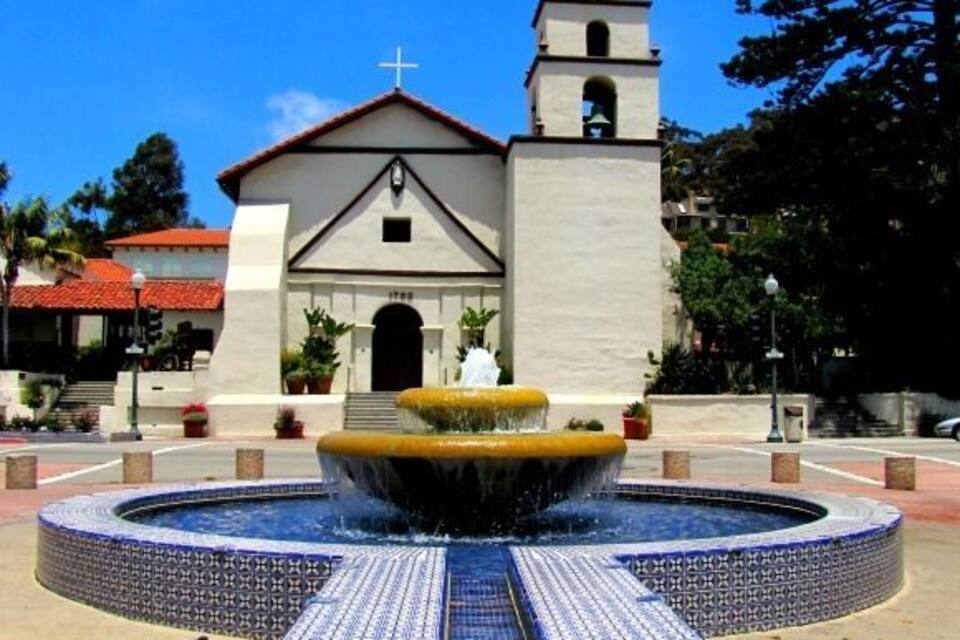 A church with a bell tower and a fountain in front.