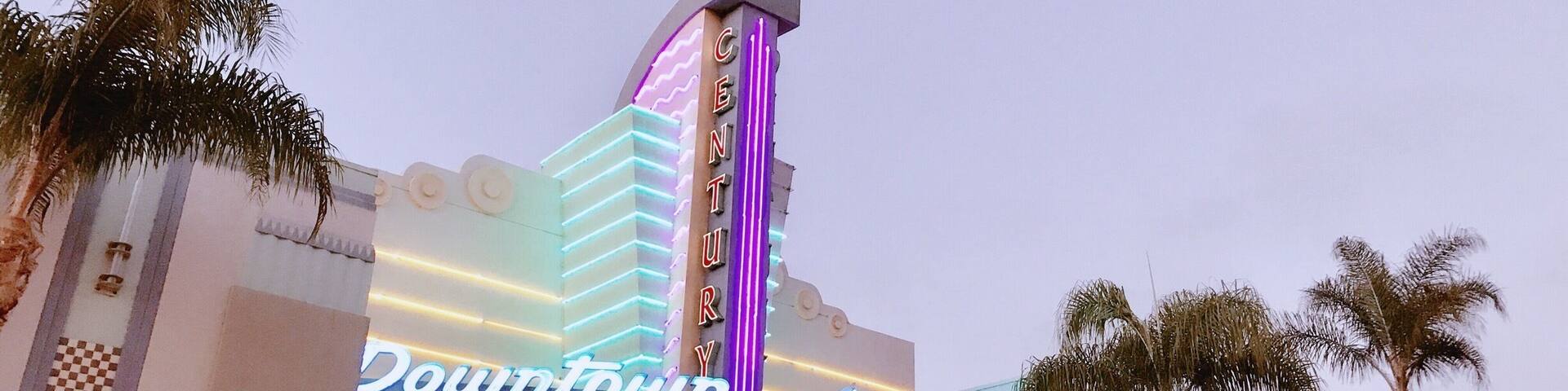 A building with a neon sign reading "Downtown" and a tall pillar with "Century" written on it.