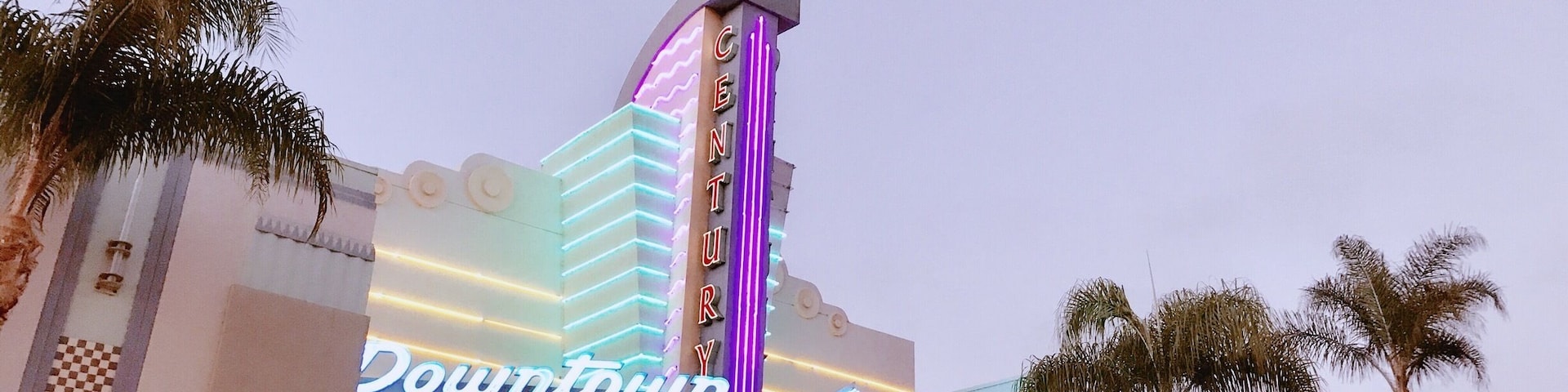 Um edifício com um letreiro de neon que diz "Downtown" e um pilar alto com a palavra "Century" escrita.