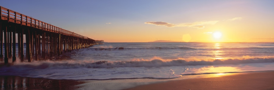 Un muelle de madera que se adentra en el océano al atardecer.