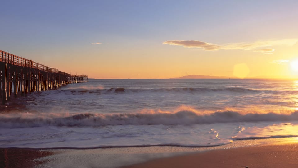 A wooden pier extending into the ocean at sunset.