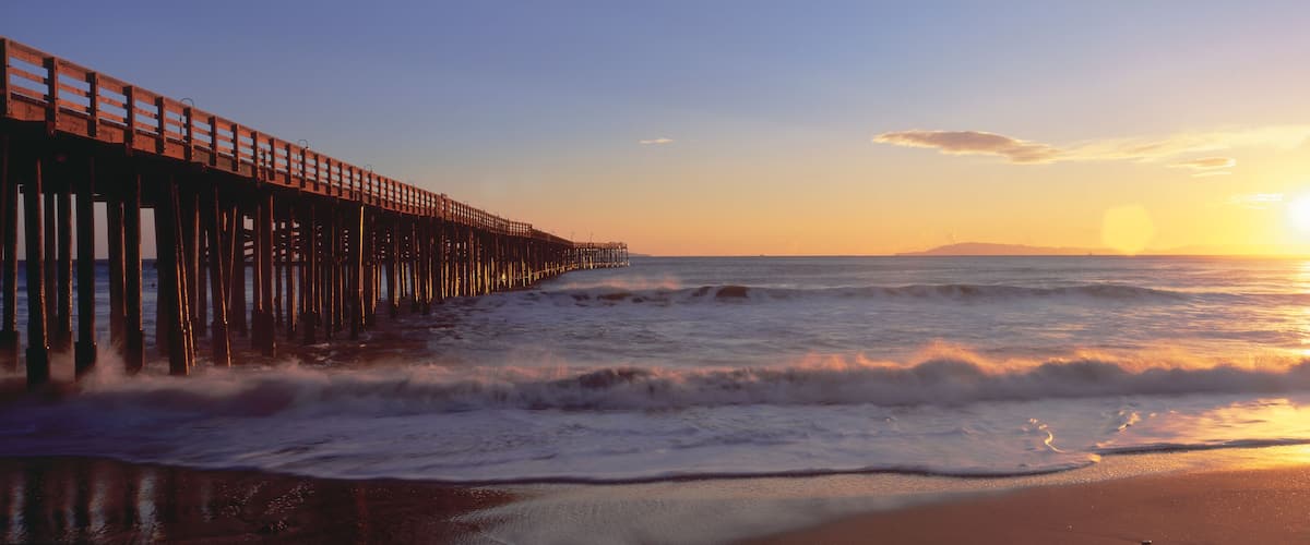 A wooden pier extending into the ocean at sunset.