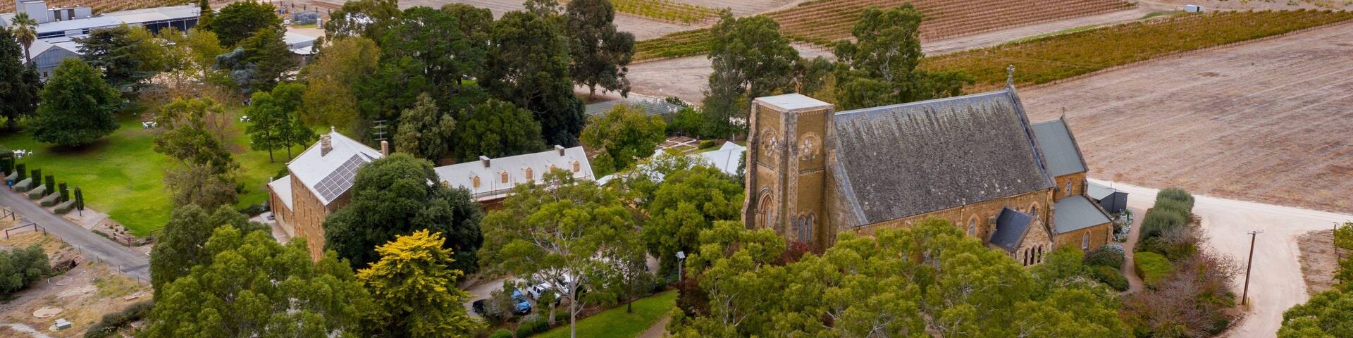An aerial view of a rural estate with a large church, surrounding fields, and scattered trees.