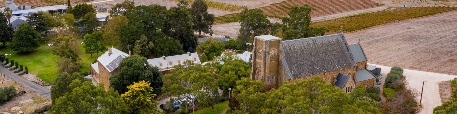 An aerial view of a rural estate with a large church, surrounding fields, and scattered trees.