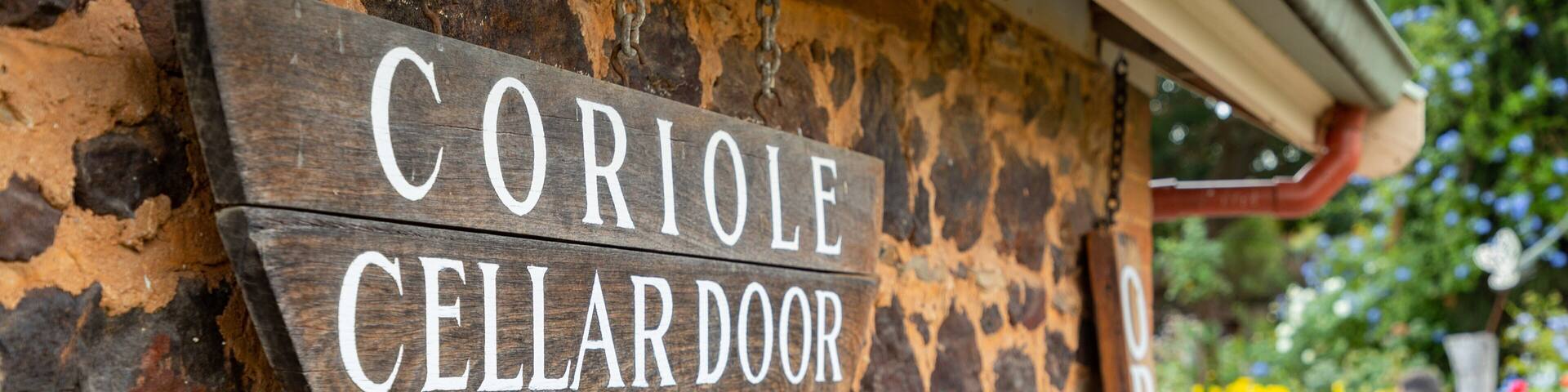 A wooden sign on a stone wall that reads "CORIOLE CELLARDOOR".