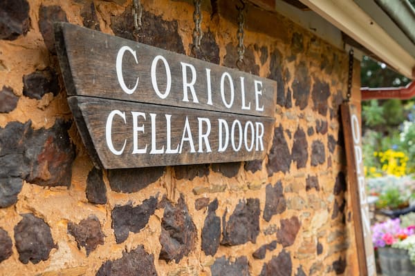 Une enseigne en bois, fixée à un mur de pierre, sur laquelle on peut lire : « CORIOLE CELLARDOOR ».