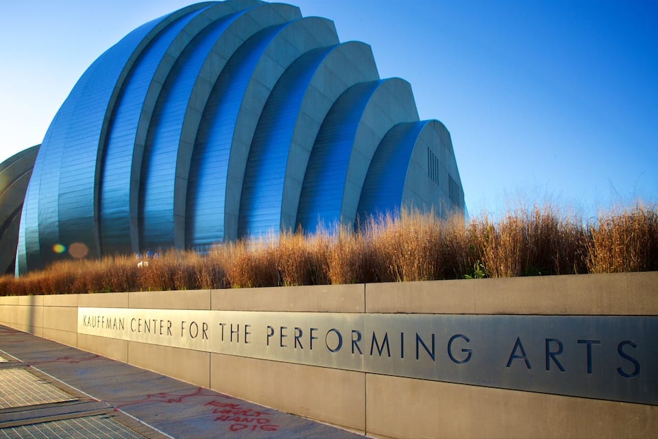 A modern performing arts center with a curved blue facade and a sign reading "Kauffman Center for the Performing Arts".