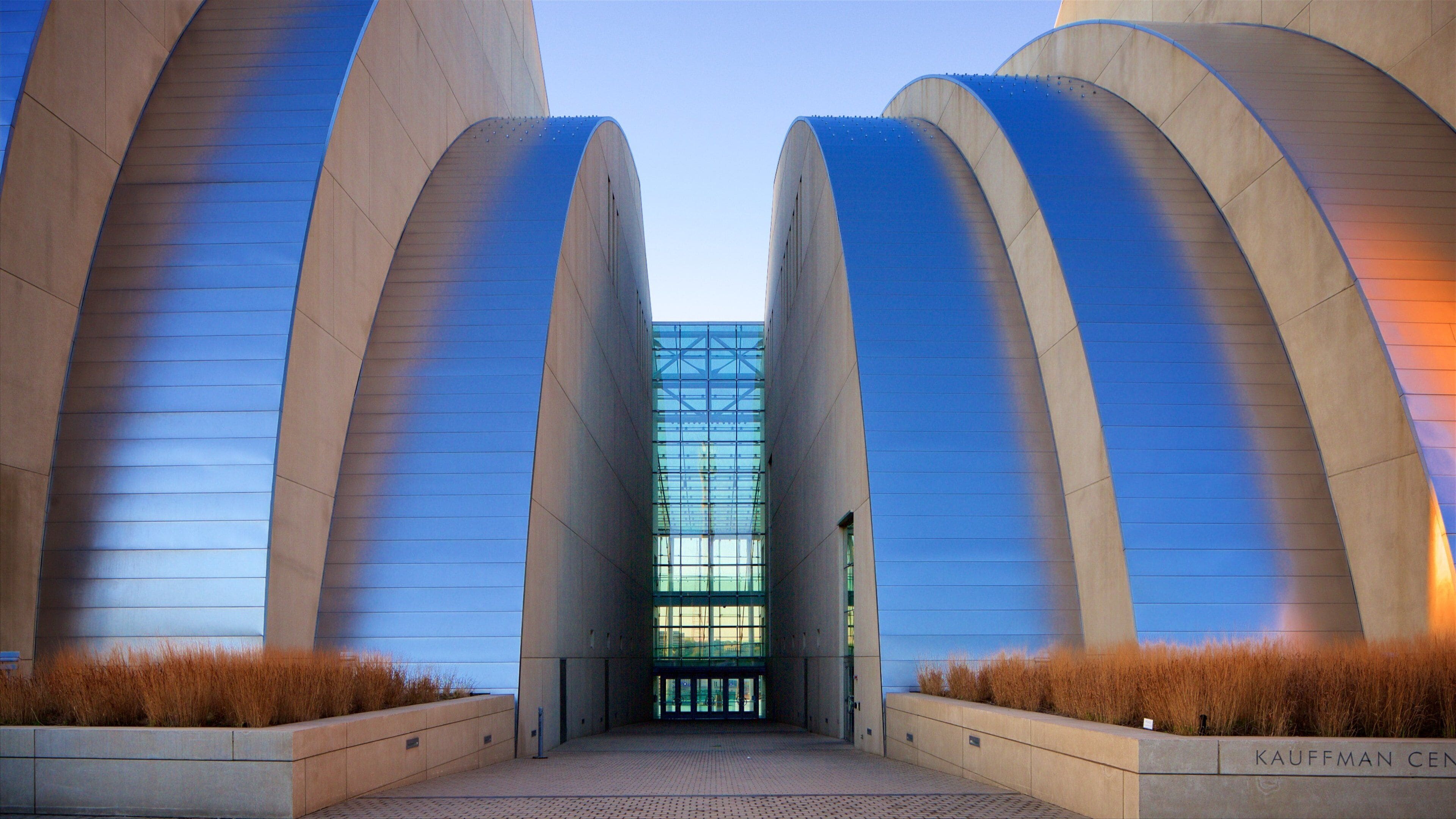 A modern building with two large, curved structures and a central glass facade.